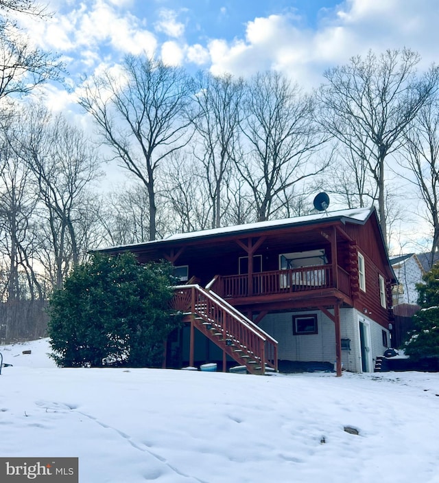 view of front of house featuring a deck, stairway, and log siding