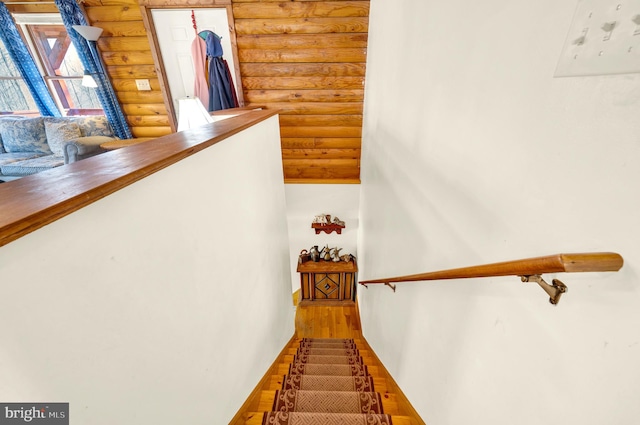 stairs featuring rustic walls and wood finished floors