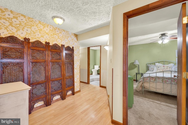 interior space with wood finished floors, a textured ceiling, baseboards, and wallpapered walls