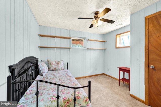 bedroom featuring a textured ceiling, light carpet, a ceiling fan, visible vents, and baseboards