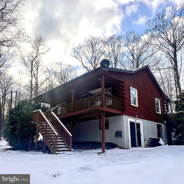 snow covered back of property featuring a wooden deck