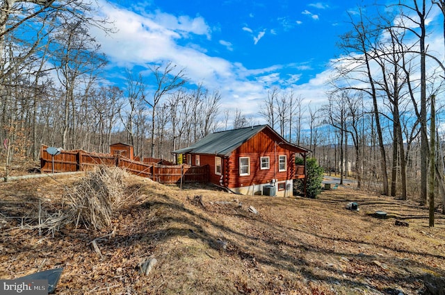 view of property exterior with metal roof, fence, log siding, and a deck