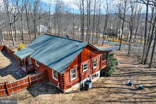 view of side of home with fence, central AC unit, metal roof, and log exterior