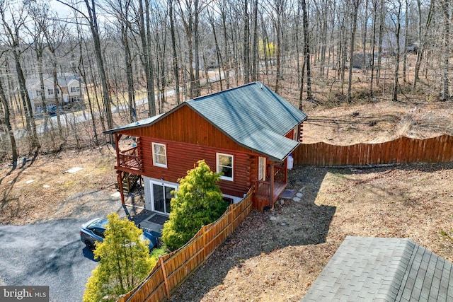 view of home's exterior with metal roof, fence, and log exterior