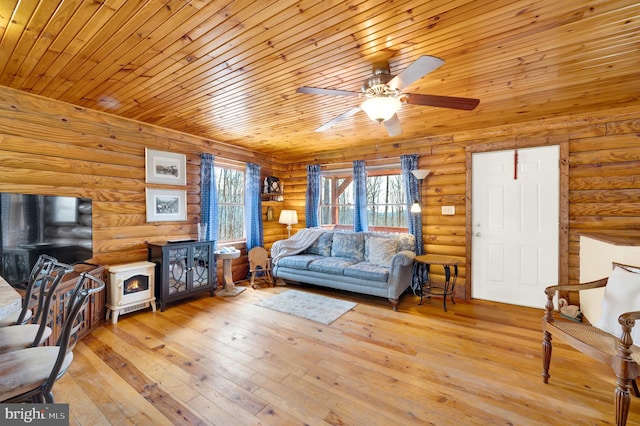 living room with ceiling fan, hardwood / wood-style floors, wooden ceiling, and a wood stove