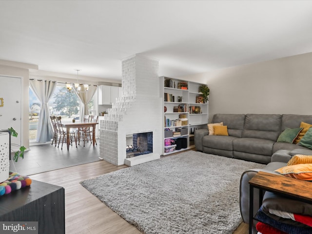 living room with a brick fireplace, light hardwood / wood-style flooring, and a chandelier