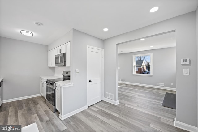 kitchen featuring stainless steel appliances, white cabinets, and light wood-type flooring