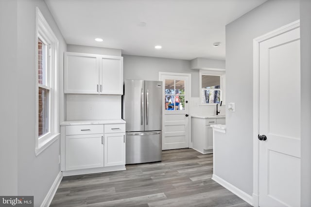 kitchen with white cabinetry, stainless steel fridge, sink, and light hardwood / wood-style flooring