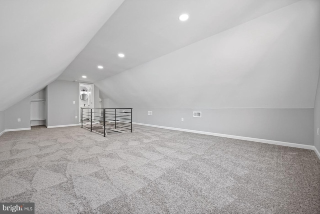 additional living space featuring vaulted ceiling and light colored carpet