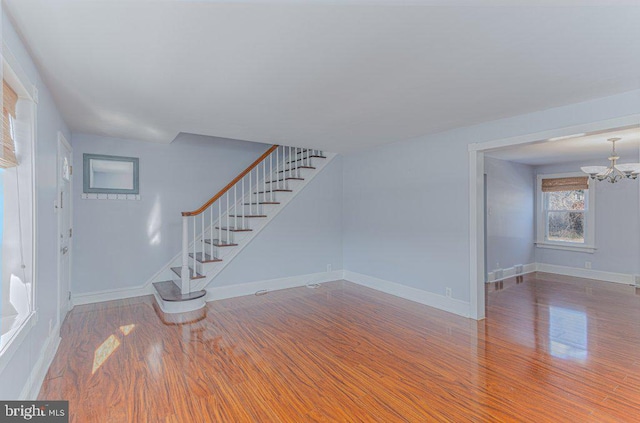 unfurnished living room with a notable chandelier and wood-type flooring