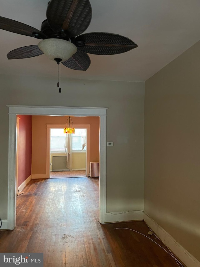 empty room featuring hardwood / wood-style flooring, radiator, and ceiling fan