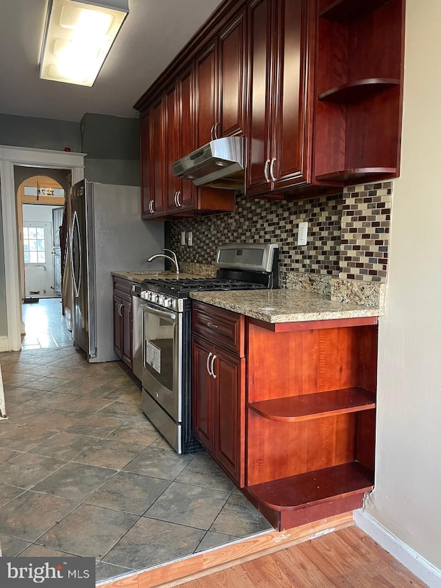 kitchen featuring stainless steel appliances, light stone countertops, and decorative backsplash