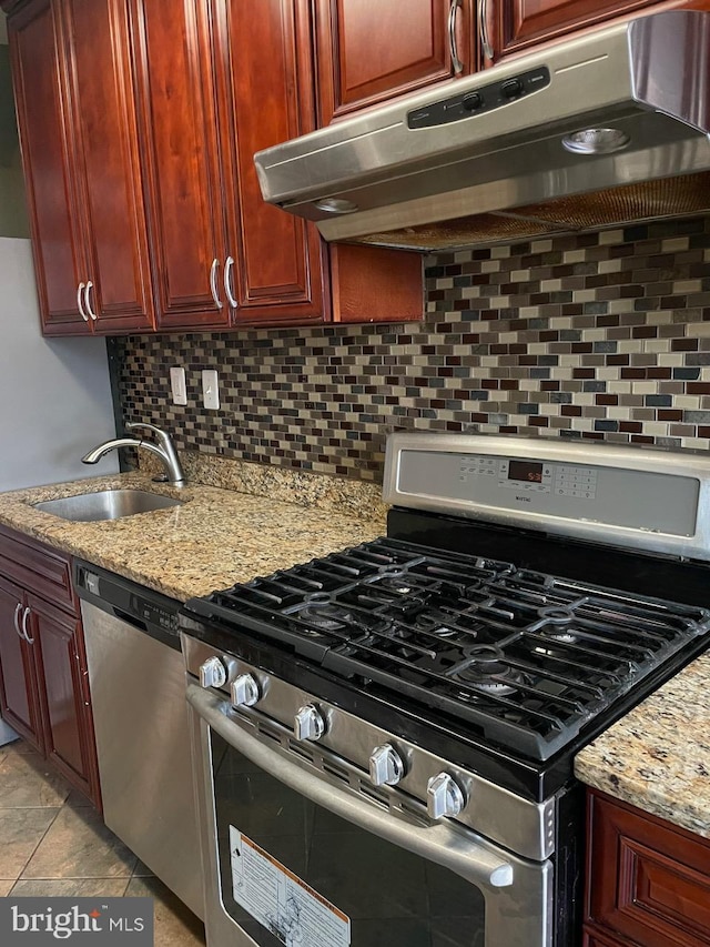 kitchen featuring sink, light stone counters, light tile patterned floors, appliances with stainless steel finishes, and backsplash