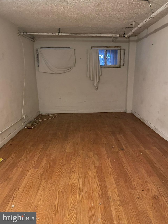 basement featuring wood-type flooring and a textured ceiling