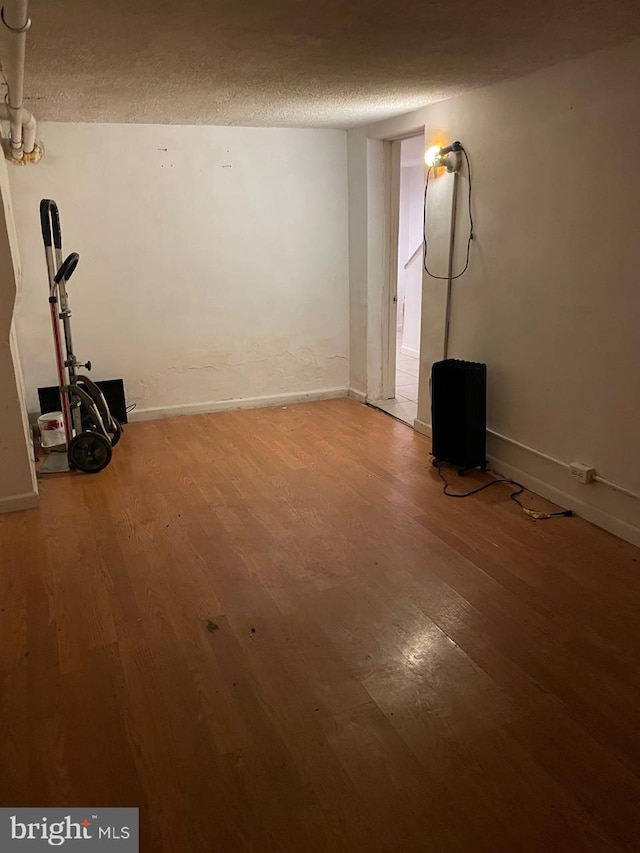 basement with wood-type flooring and a textured ceiling