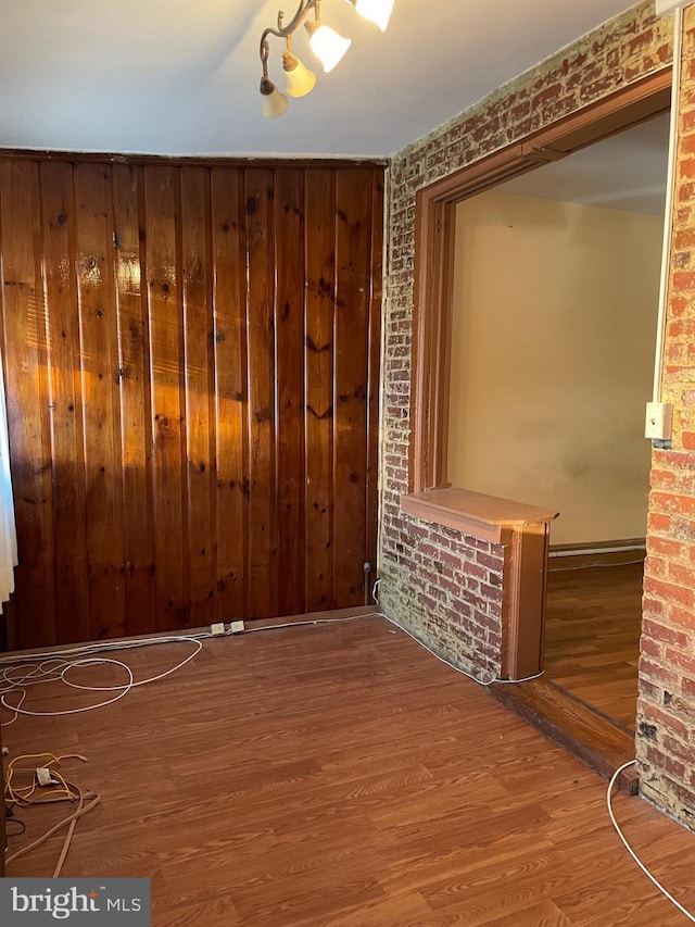 empty room featuring hardwood / wood-style flooring and brick wall