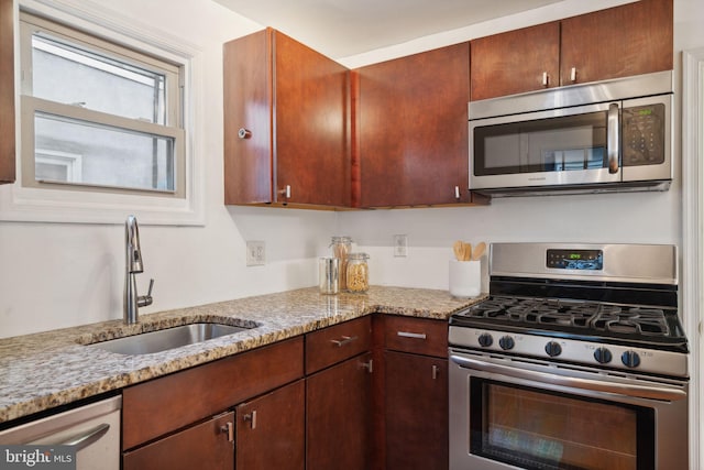 kitchen featuring appliances with stainless steel finishes, light stone countertops, and sink