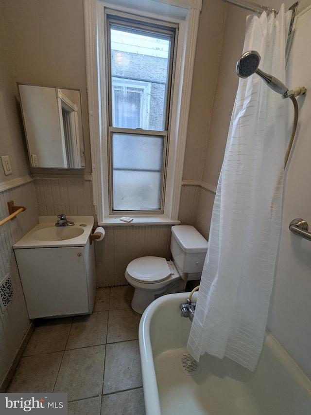 bathroom with tile patterned flooring, vanity, wood walls, and toilet