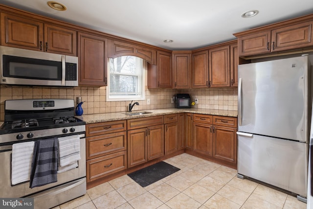 kitchen featuring light stone counters, sink, light tile patterned floors, and appliances with stainless steel finishes