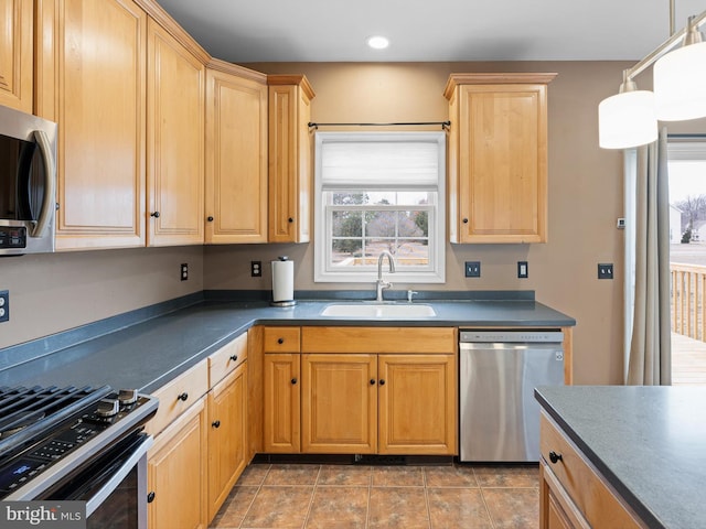 kitchen featuring recessed lighting, stainless steel appliances, a sink, hanging light fixtures, and dark countertops