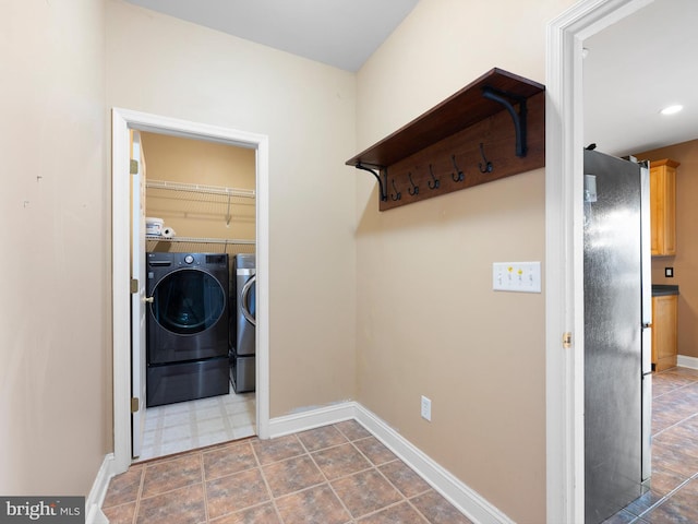 clothes washing area with laundry area, baseboards, and washer and clothes dryer