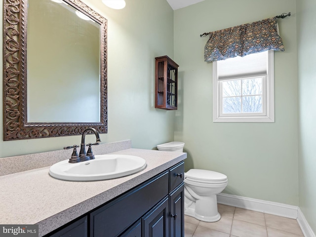 bathroom with toilet, tile patterned flooring, vanity, and baseboards