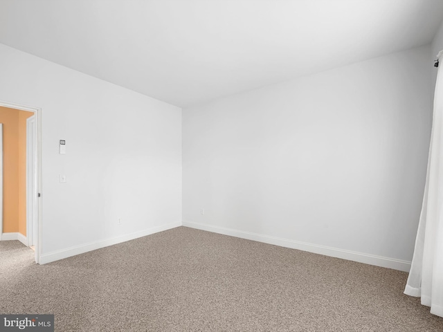 spare room featuring carpet floors and baseboards