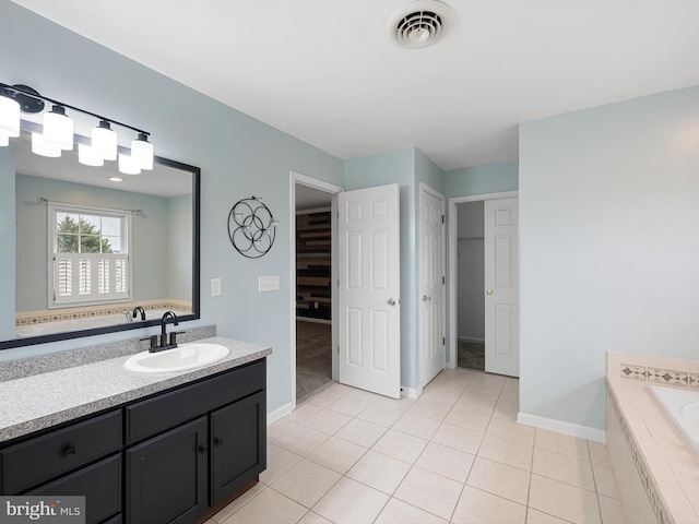 full bath featuring tiled bath, vanity, visible vents, a closet, and tile patterned floors