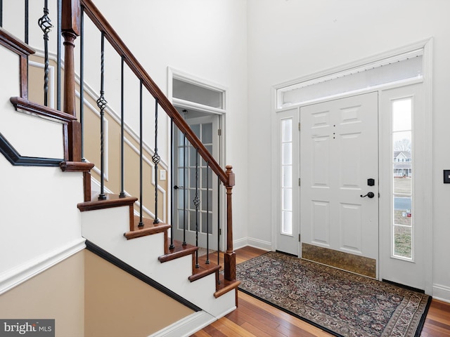 foyer with stairs, a high ceiling, baseboards, and wood finished floors