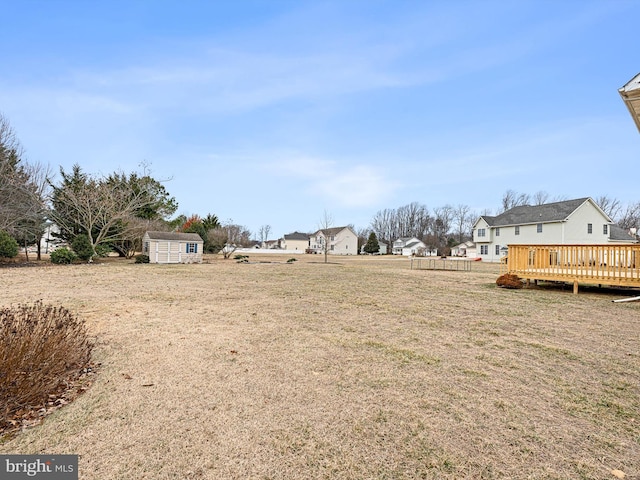 view of yard featuring a deck, a storage shed, an outdoor structure, and a residential view