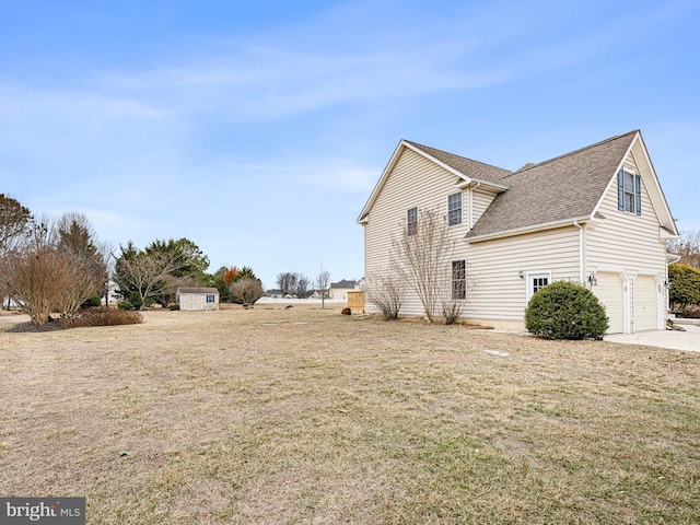 view of home's exterior featuring an attached garage, a storage shed, a shingled roof, driveway, and a lawn