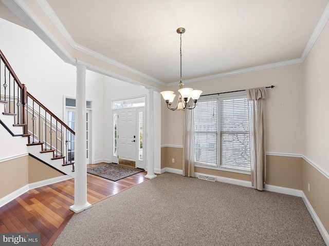 foyer entrance with ornate columns, baseboards, visible vents, and crown molding