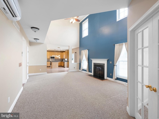 unfurnished living room with a glass covered fireplace, a wall mounted air conditioner, plenty of natural light, and light carpet