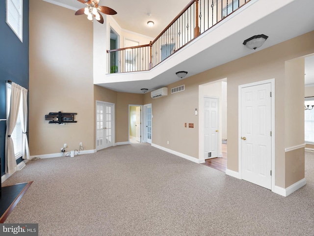 unfurnished living room with carpet floors, baseboards, visible vents, and an AC wall unit