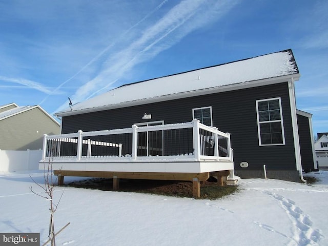 snow covered back of property with a deck