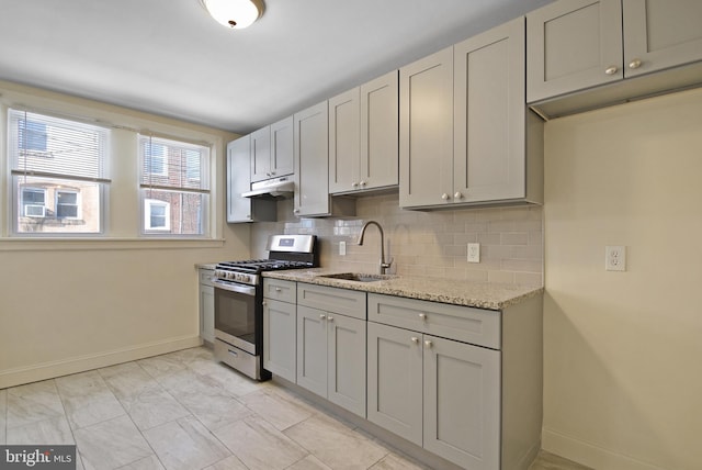 kitchen featuring gray cabinets, sink, decorative backsplash, light stone countertops, and stainless steel gas range