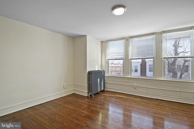 empty room with dark hardwood / wood-style flooring and radiator heating unit