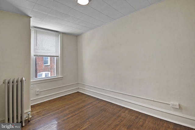 empty room featuring radiator and dark wood-type flooring