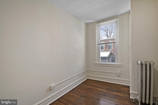 unfurnished room featuring radiator heating unit and dark hardwood / wood-style flooring