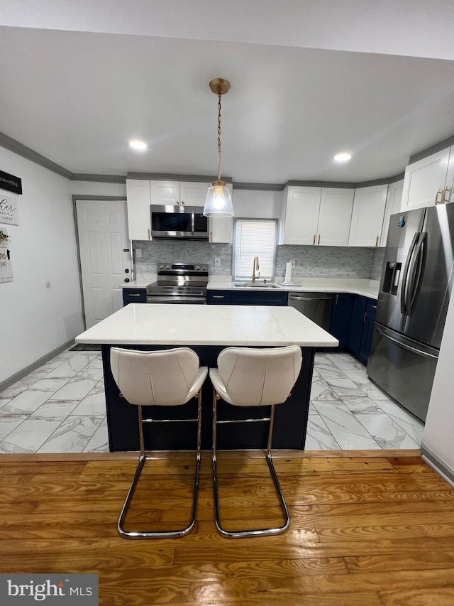 kitchen featuring blue cabinetry, white cabinetry, a kitchen breakfast bar, a kitchen island, and stainless steel appliances