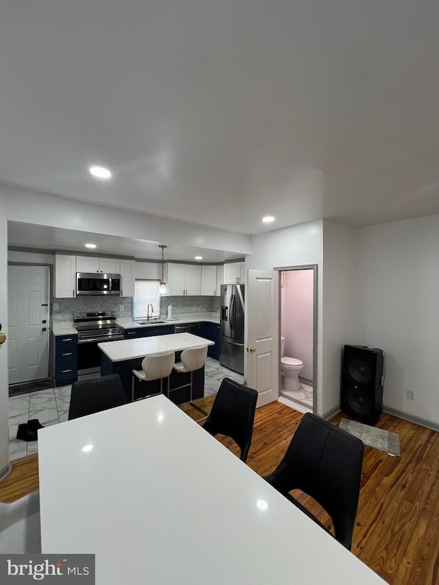 kitchen with sink, appliances with stainless steel finishes, hanging light fixtures, a center island, and white cabinets