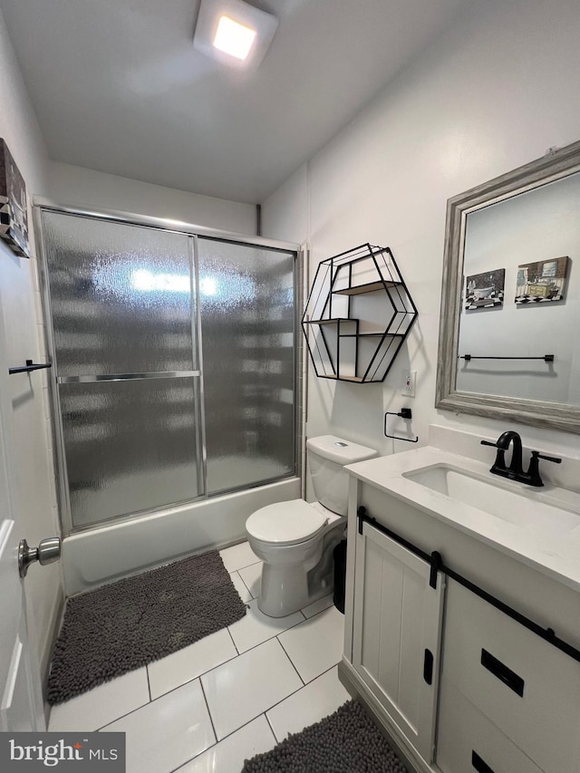 full bathroom featuring tile patterned flooring, vanity, combined bath / shower with glass door, and toilet