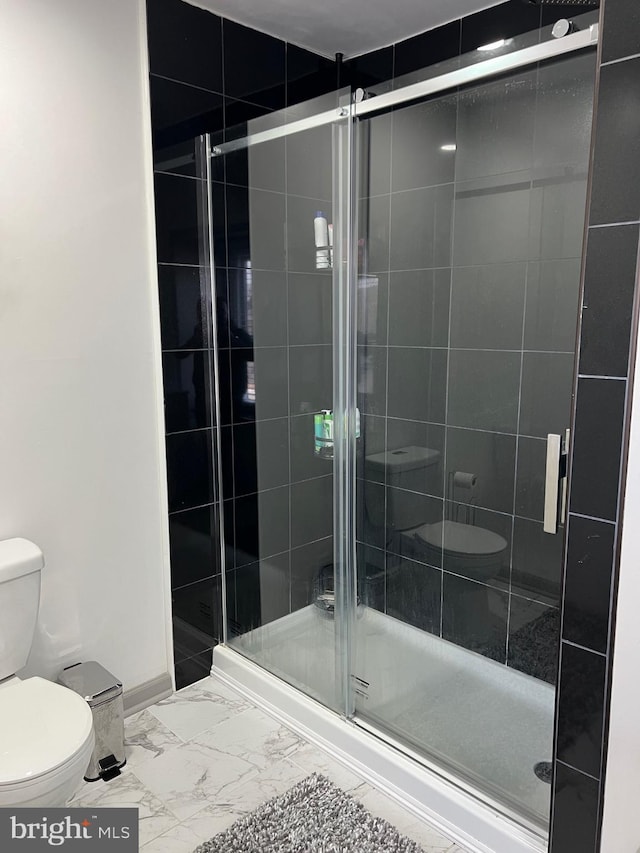 bathroom featuring a shower with door and toilet