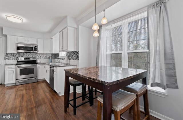 kitchen with stainless steel appliances, white cabinetry, plenty of natural light, and pendant lighting