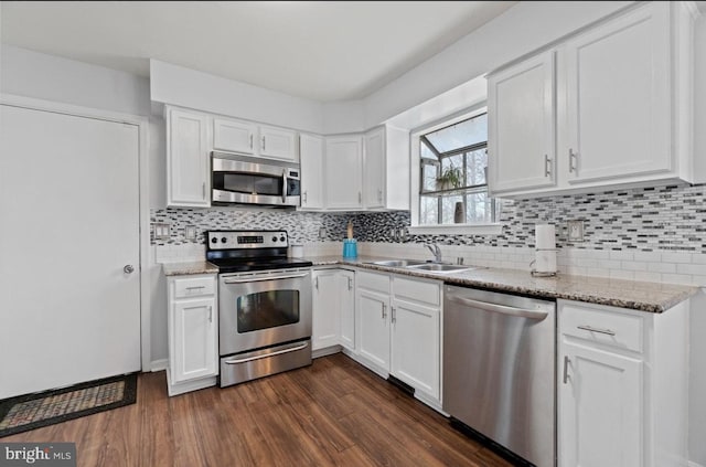 kitchen with appliances with stainless steel finishes, sink, white cabinets, and dark hardwood / wood-style floors