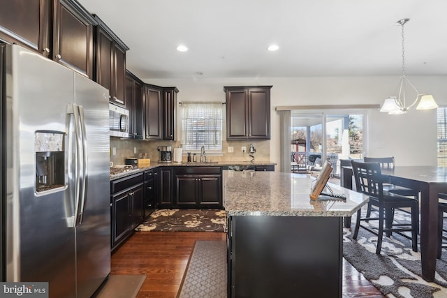 kitchen featuring a kitchen island, dark hardwood / wood-style floors, pendant lighting, tasteful backsplash, and stainless steel appliances