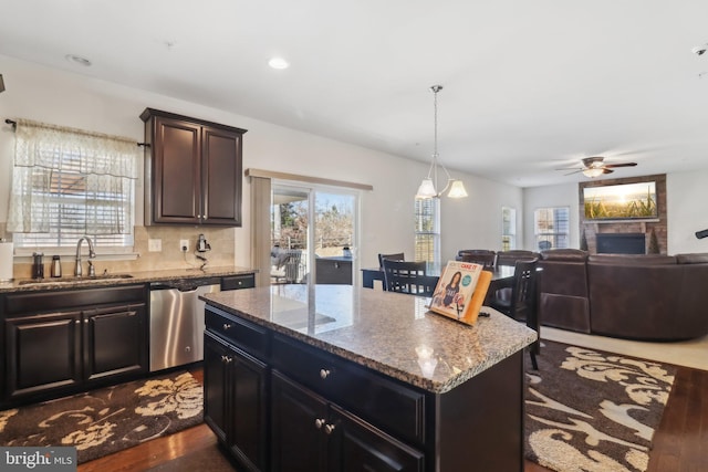 kitchen with dark wood-type flooring, sink, dishwasher, a kitchen island, and pendant lighting