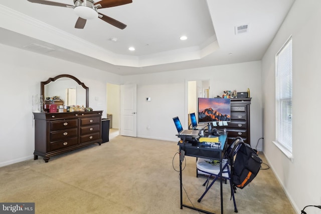 office space featuring a raised ceiling, crown molding, light colored carpet, and ceiling fan