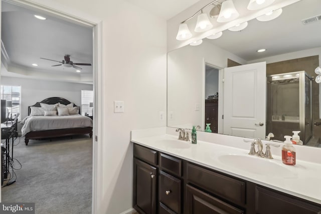 bathroom featuring a raised ceiling, vanity, an enclosed shower, and ceiling fan