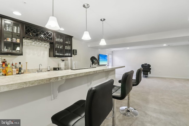 bar featuring sink, light carpet, dark brown cabinetry, and decorative light fixtures